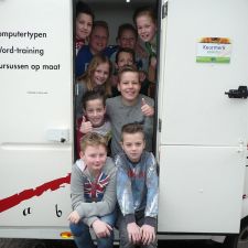 Kinderen zitten in de deuropening van de Typejuf caravan