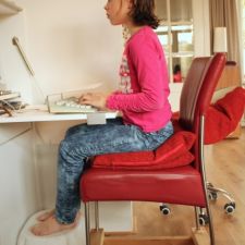 Meisje maakt huiswerk achter de computer met afgeschermd toetsenbord